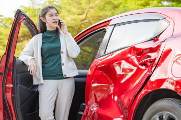Vrouw staat naast auto met een diepe deuk