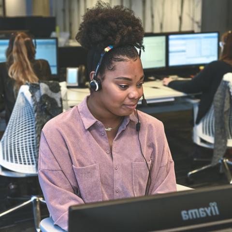 Jonge vrouw met telefonische headset achter computer